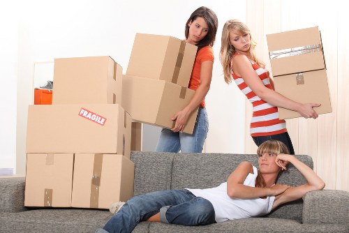 Professional movers handling furniture in a residential street near Elmstead